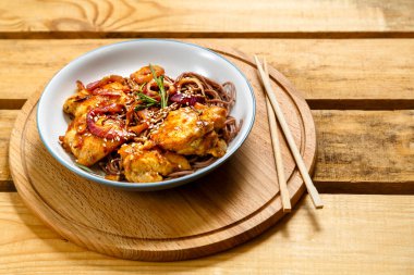 Tahta bir standın üzerinde tavuklu soba ve teriyaki soslu susam tohumu. Yatay fotoğraf