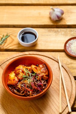 Ahşap bir standın üzerinde tavuklu susamlı ve susamlı tohumlar ve susamlı tohumlar ve ahşap bir soya sosunun yanında duruyor. Dikey fotoğraf