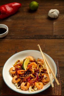 Mantarlı udon ve hafif bir tabakta karides peçete, çubuk ve malzemelerin yanında. Dikey fotoğraf