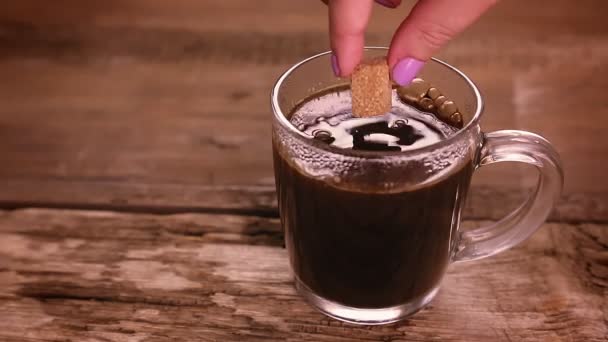 A womans hand puts pieces of brown sugar in a cup of coffee and it dissolves in the drink — Stock Video