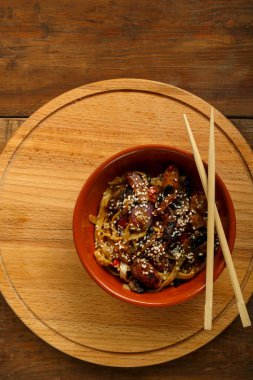 Tay soslu sebze ve mantarlı Udon ahşap bir büfede, yemek çubuklarının yanında..