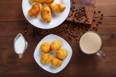 Bir kupa kremalı kahve ve bir sürahi krema ve ayçöreği dağınık kahve çekirdekleri arasında masanın üstünde..