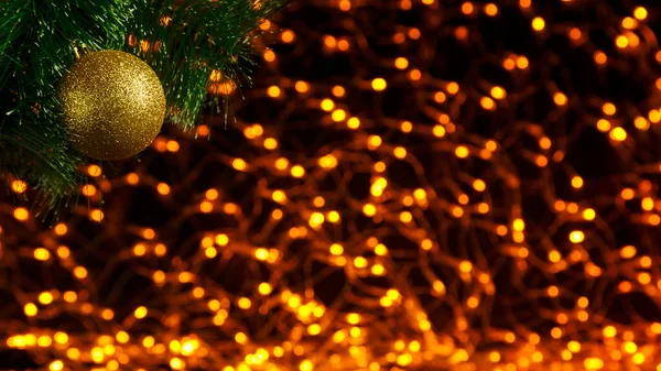 Bokeh jul bakgrund med gyllene ljus på svart i hörnet av en gren av en julgran med dekoration. — Stockfoto