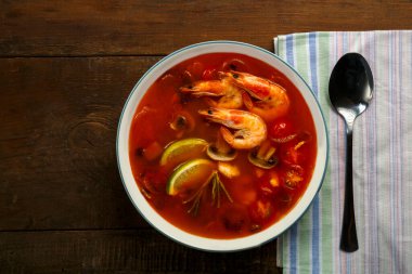 Tom peçetedeki kaşığın yanında karides ve limonlu tatlı patates çorbası..