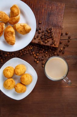 Şeffaf bir kupa, kremalı kahve, bir sürahi krema ve ayçöreği dağınık kahve çekirdekleri arasında masanın üzerinde..