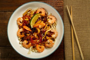 Peçete ve yemek çubuklarının yanında hafif bir tabakta sebzeli, mantarlı ve karidesli udon..