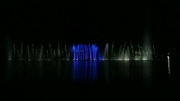 Фонтаны показывают на фоне ночного неба разноцветные струи и комбинации — стоковое видео