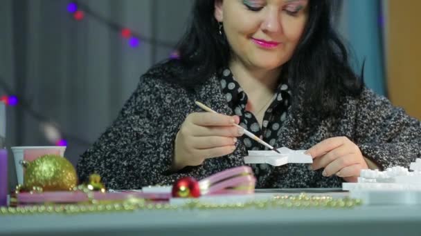 テーブルの若い女性は、水彩で白いブランクを描くことによってクリスマスのための家の装飾を作ります。パノラマ — ストック動画