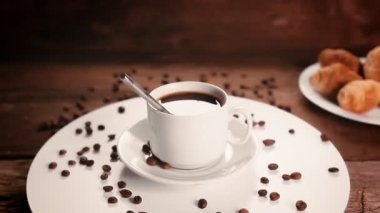 Bir fincan kahveyi kaşıkla tepside dağılmış kahve çekirdekleri daire şeklinde döner.