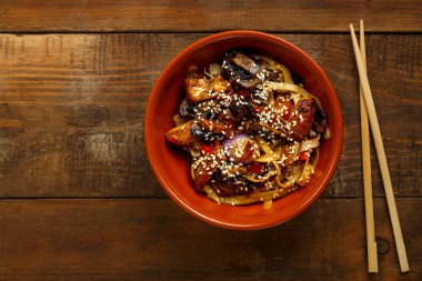 Tay soslu sebzeler ve mantarlar çubukların yanındaki kil tabakta..