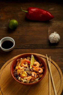 Mantarlı udon ve kilden bir tabakta karides yemek çubuklarının yanında yuvarlak bir standı var..