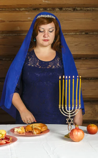 Еврейская женщина за столом в канун Рош ха-Шана стоит рядом с горящими свечами. — стоковое фото
