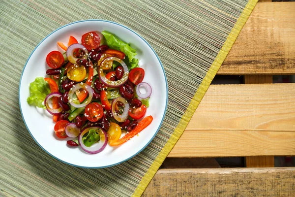 Licht bord met pan-Aziatische salade met sesamzaad en tamarinde op een bamboe tafelkleed en een houten tafel. — Stockfoto