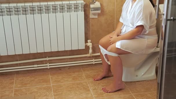 Una mujer con una bata blanca se sienta en el baño en el baño. Disparos sin rostro. — Vídeos de Stock