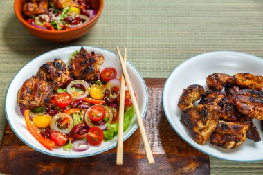 Pan-Asya susam ve demirhindi salatası tabakları ve Tayland soslu ızgara tavuk parçaları..