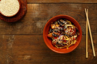 Tay soslu sebzeler ve mantarlar çubukların yanındaki kil tabakta..