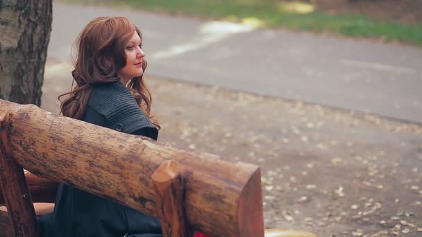 Mulher com cabelo castanho em um banco de parque no outono. — Vídeo de Stock