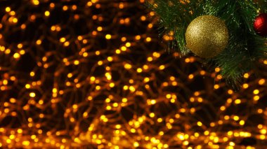 Bokeh Yeni Yıl arkaplanı, süslenmiş bir Noel ağacının dalının köşesinde siyah üzerine altın ışıklar..