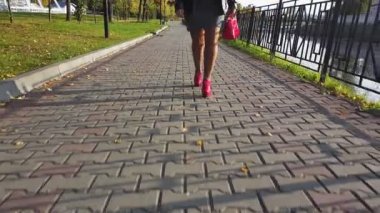 Kırmızı çizmeli kadın ayaklar kaldırımlı yolda yürüyor..