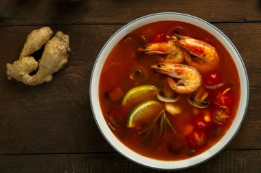 Tom zencefilin yanındaki hafif tabakta karides ve limonlu tatlı patates çorbası..