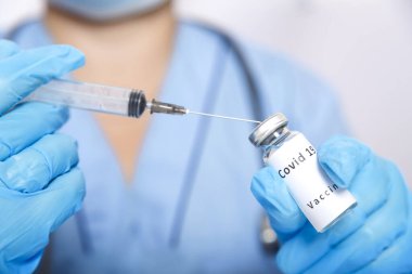 Eldivenli bir doktor şırıngayı koronavirüs aşısıyla doldurur..