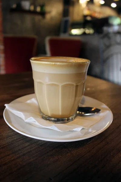 A cup of hot cafe latte (plus its latte art) served at a cafe.
