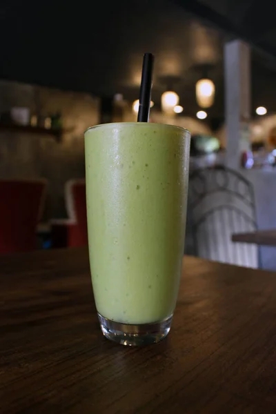 A cup of cold green avocado juice served at a cafe