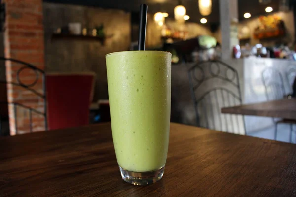 冷たい緑のアボカド ジュースのカップをカフェで提供しています — ストック写真