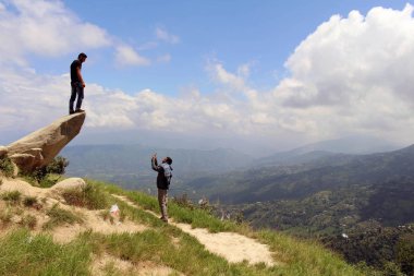 İyi Nepalce arkadaş bir taş üzerinde fotoğraf çekmek için yardımcı oluyor. Dhulikhel, Nepal, Ağustos 2018 alınan.