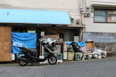 Beppu, Oita, Japonya 'da bir ev ya da mağazanın önünde motosiklet ve eşyalar. Haziran 2019 'da çekildi..