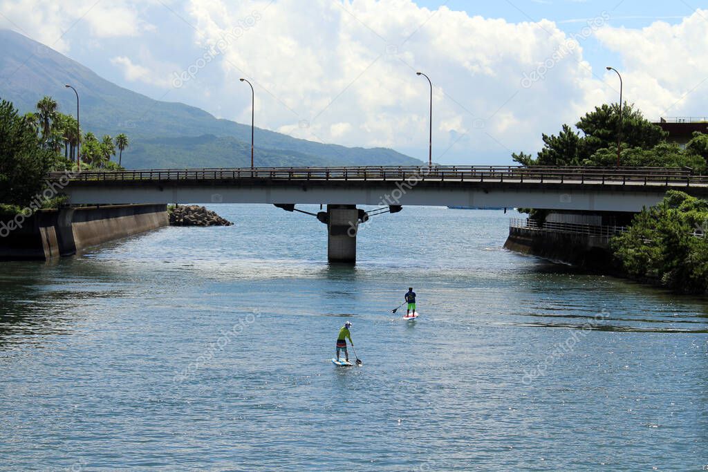 People paddling under the bridge overlooking Sakurajima of Kagoshima. Taken in August 2019.