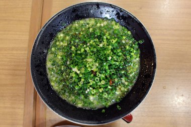 Bir kase domuz etli ramen tonkotsu dilimlenmiş taze soğan ya da Kagoshima 'da pırasa ile kaplı..