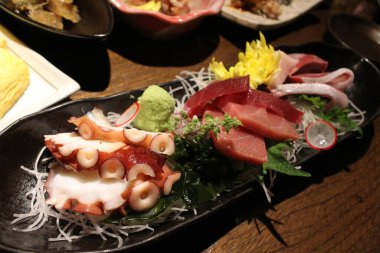 Balık, ahtapot ve wasabi dolu bir tabak saşimi Japon izakaya 'sında servis edilir.