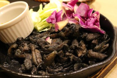 Siyah bir tabakta Japon izakayasında servis edilen kızarmış siyah kömür tavuğu.