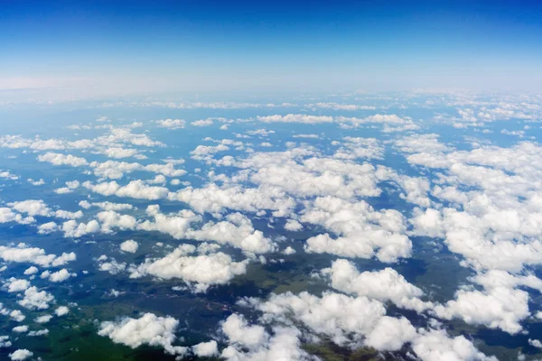 View of clouds above the ground from an airplane window