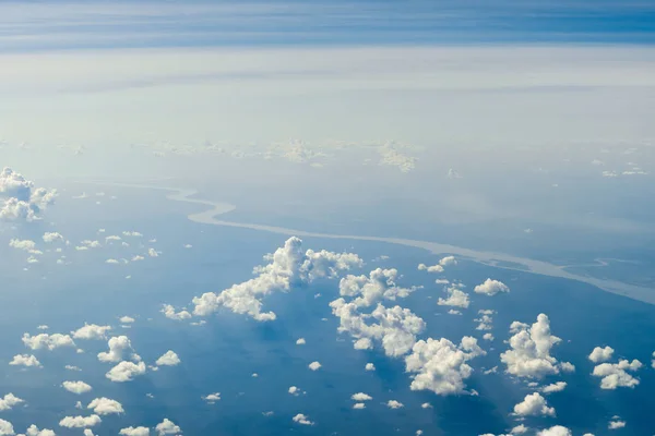 Clouds high above the earth and the river, view from airplane window