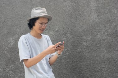 akıllı telefon kullanarak şapka ve gözlük ile çekici genç asyalı adam
