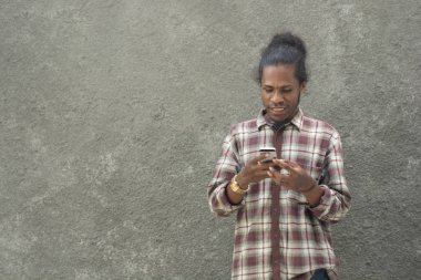 Genç sakallı siyah adam, akıllı telefon kullanıyor.