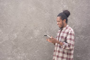 Tablet ya da laptop kullanan sıradan giysili genç sakallı siyahi adam., 