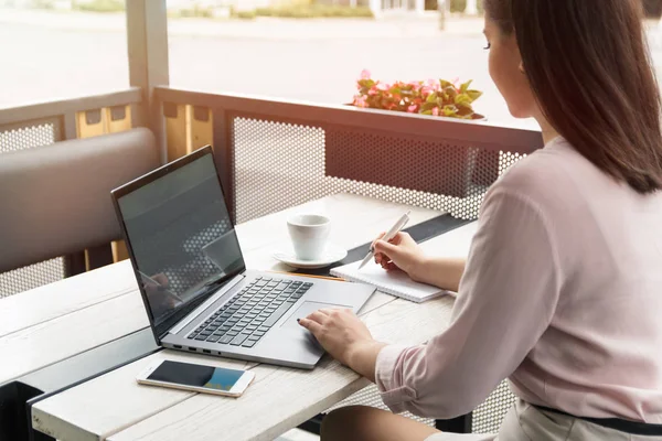 Laptop ve yazma, kahve tablo üzerinde çalışan genç bir kadın portresi kapatın.