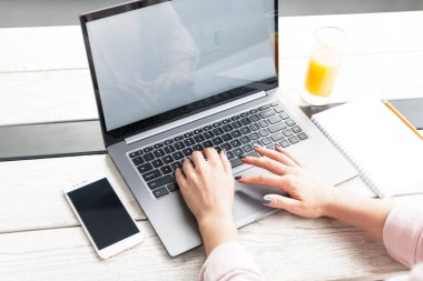 Laptop ve yazma, masanın üzerine portakal suyu üzerinde çalışan genç bir kadın portresi kapatın.