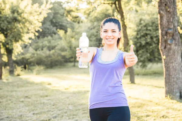 Молодая женщина пьет воду после тренировки, чувствует себя хорошо. Активный образ жизни . — стоковое фото