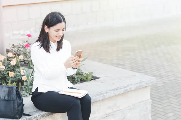 Estudiante feliz usando un smartphone en una ciudad cercana a la universidad . — Foto de Stock