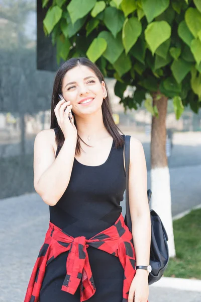 Atractiva mujer de negocios morena hablando por teléfono móvil con el cliente en la calle — Foto de Stock