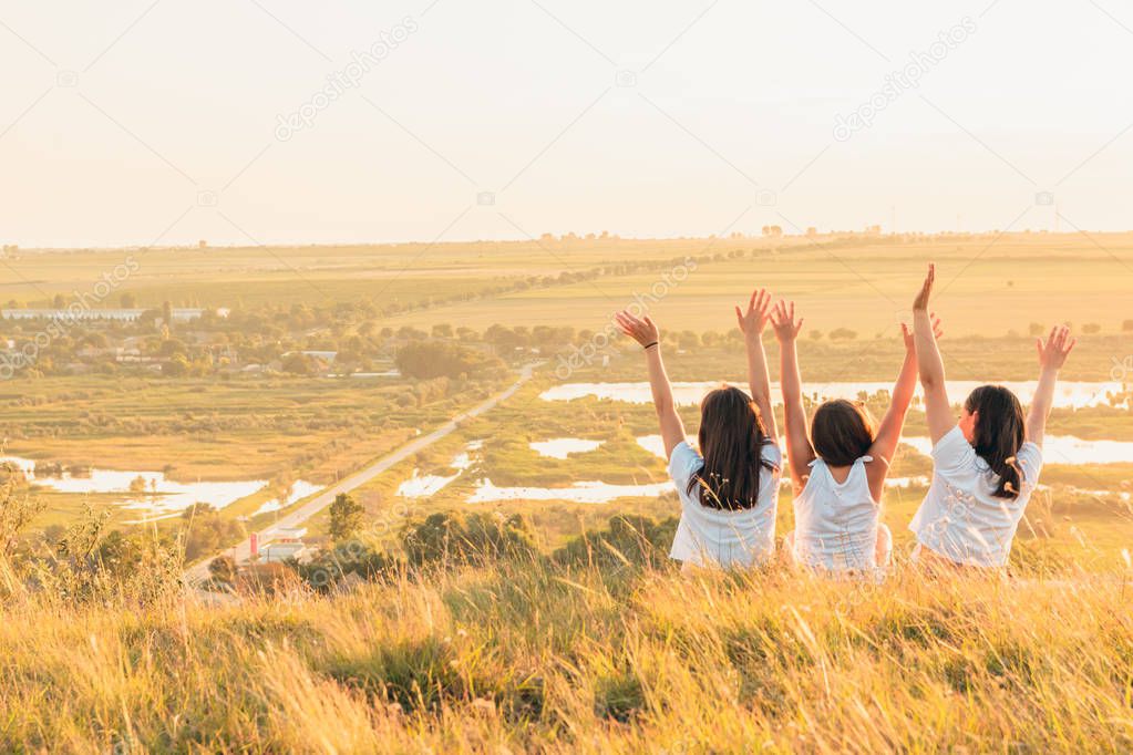 Group of three girls enjoying the sunset on a hill at countryside