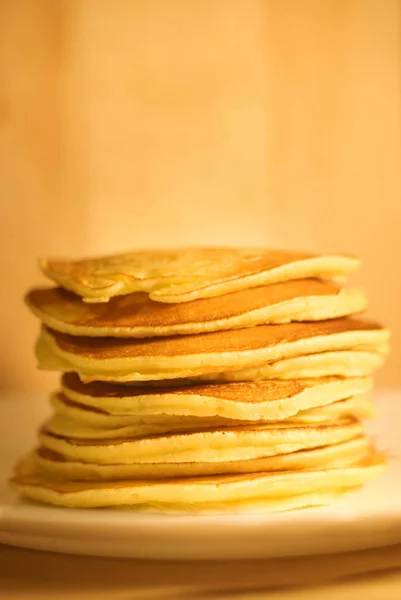 Tasty pancakes on white plate, wood background — Stock Photo, Image
