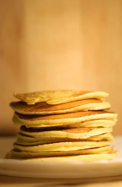 Tasty pancakes on white plate, wood background — Stock Photo, Image