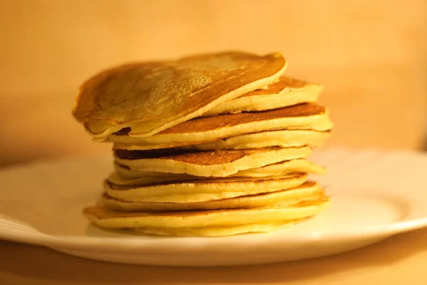 Tasty pancakes on white plate, wood background — Stock Photo, Image