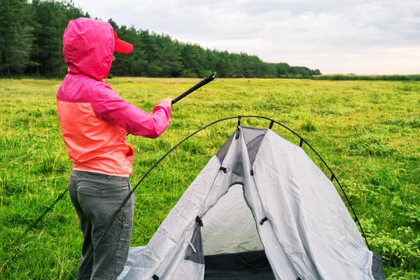 Mädchen in pinkfarbener Jacke mit Kapuze baut Zelt auf — Stockfoto