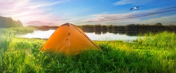 Апельсиновая палатка на берегу озера — стоковое фото